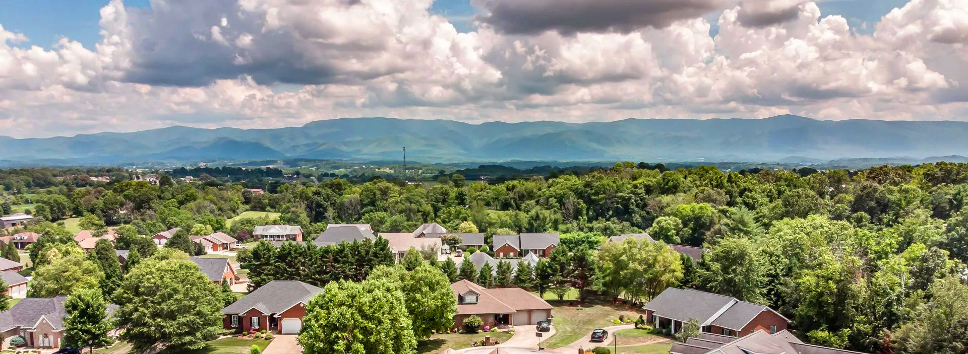 View of Greene Mountain and Viking Mountain seen from a drone hovering over a Greeneville Tennessee subdivision with large homes with swimming pools
